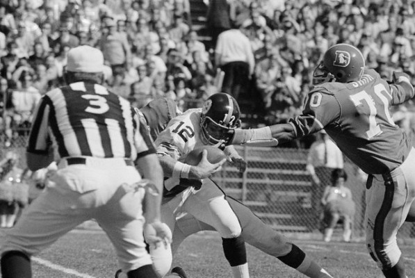 27 Sep 1970, Denver, Colorado, USA --- Denver Bronco tackle (#70) Paul Smith begins his tackle on Pittsburgh quarterback (#12) Terry Bradshaw eye level. Smith dropped the Steelers Bradshaw for a 12-yard 1st quarter loss. Denver won, 16-13. --- Image by © Bettmann/CORBIS