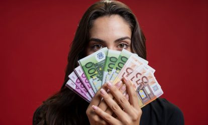 vrouw die haar gezicht bedekt met geld Financiële (on)afhankelijkheid van vrouwen en partnergeweld