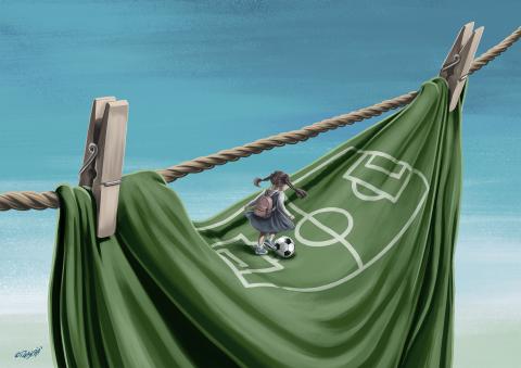 A girl carrying a backpack walks along a clothesline above a hanging cloth painted as a football field, with a football resting on it.