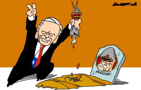 Cartoon showing Jose Antonio Kast standing by the grave of Augusto Pinochet; he's holding up one hand with two fingers extended in a victory sign; in the other hand he's holding the skeletal arm of Pinochet (still wearing a general's uniform sleeve), which is also giving a victory sign.