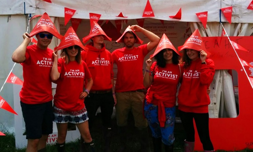 10 - I'm-an-Activist-for-Action-for-Children-promotional-staff-with-stand-next-to-Glastonbury-pyramid-stage-by-Neon-1200x720