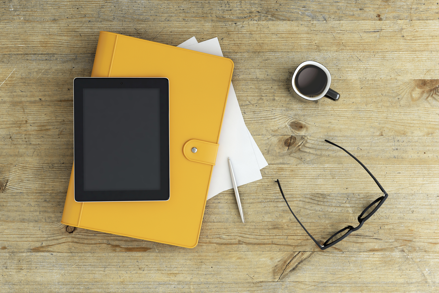 View from above on a working desk setup, bright yellow notebook, notes, coffee and glasses