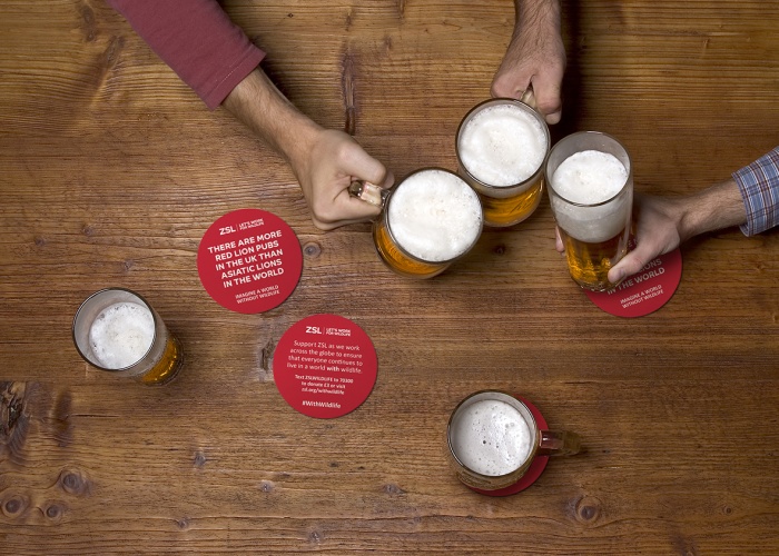 three people drinking beer at the wooden table at pub