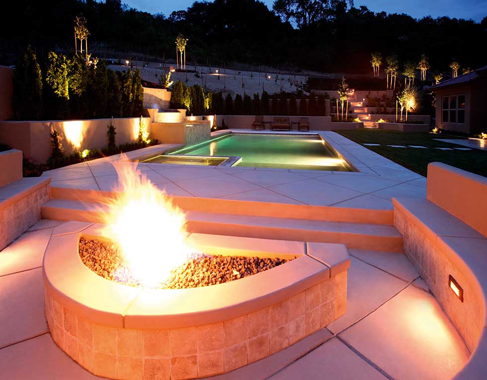 fire pit and pool at night in a luxury garden