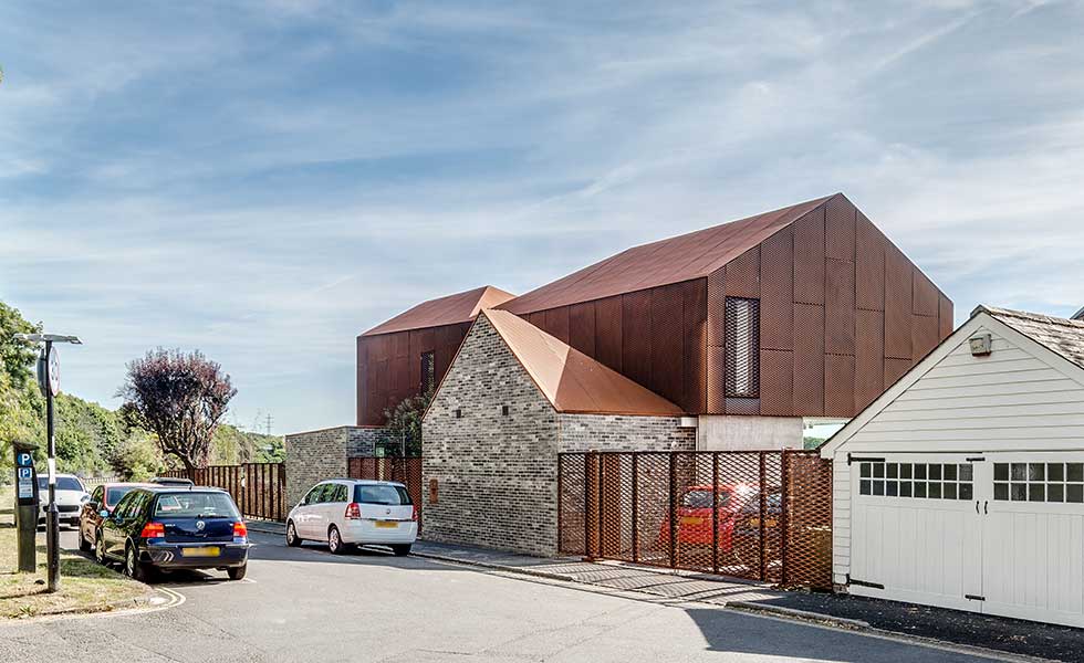 street view of modern home with metal upper and glass and stone lower