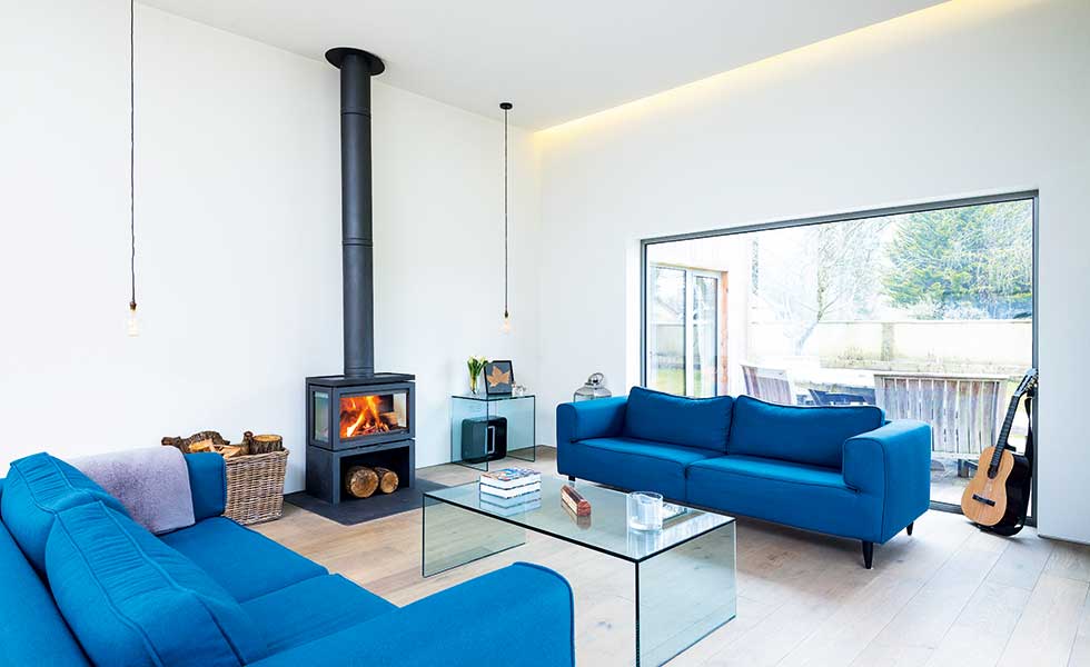 modern white living room with wood burner and blue sofas