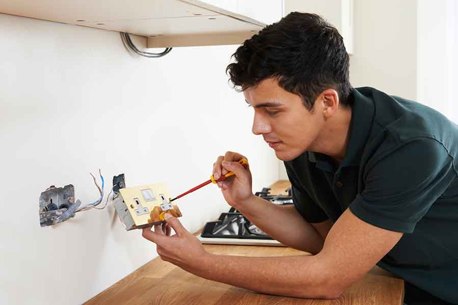 Electrician installing socket in kitchen