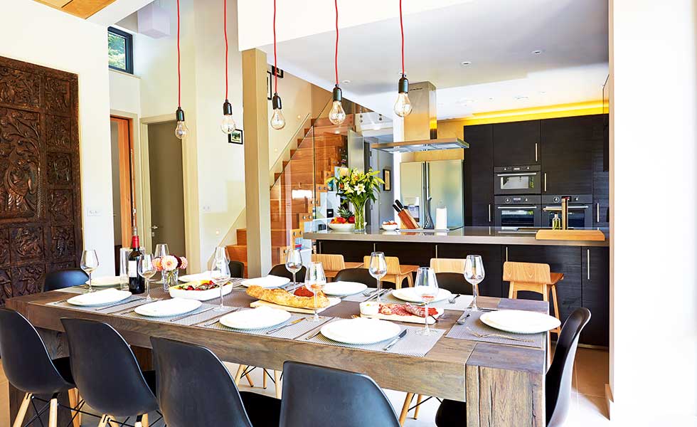 An inviting open plan dining/kitchen/living space in a woodland holiday home by CDMS Architects
