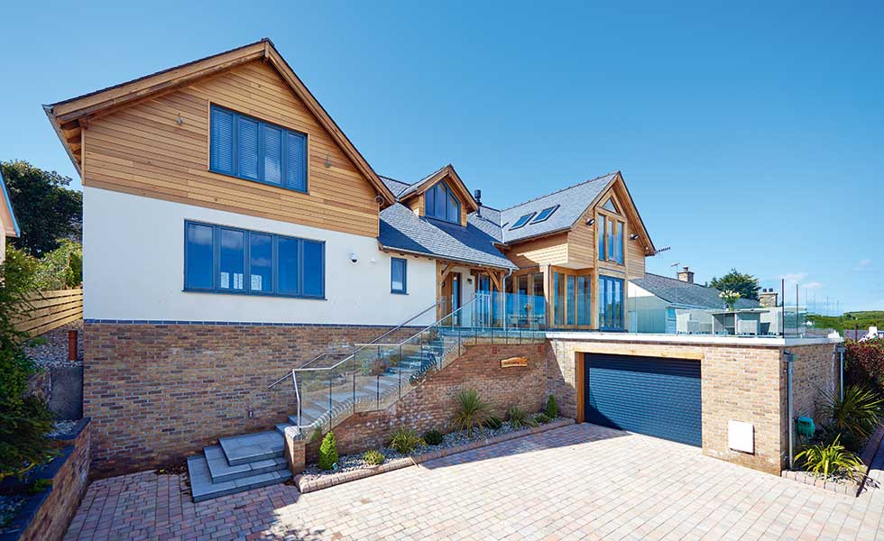 Timber clad house with render on sloping site