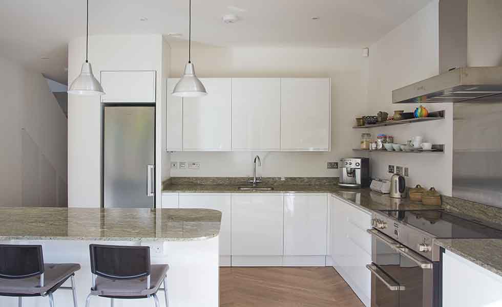 White gloss units and granite worktops feature in this prefabricated timber frame home