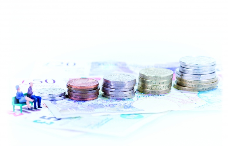 Miniature man and woman sitting on a bench beside the coins and banknotes