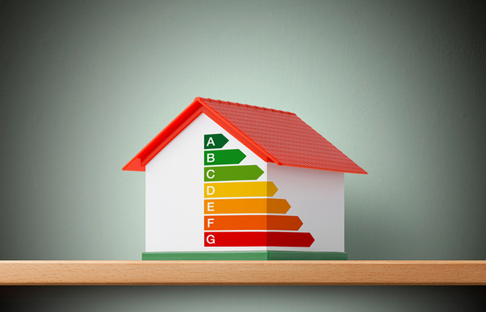 Miniature model house with energy efficiency graph.