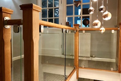 Stairfurb's oak handrail, glass panels & stainless steel brackets create a contemporary landing.