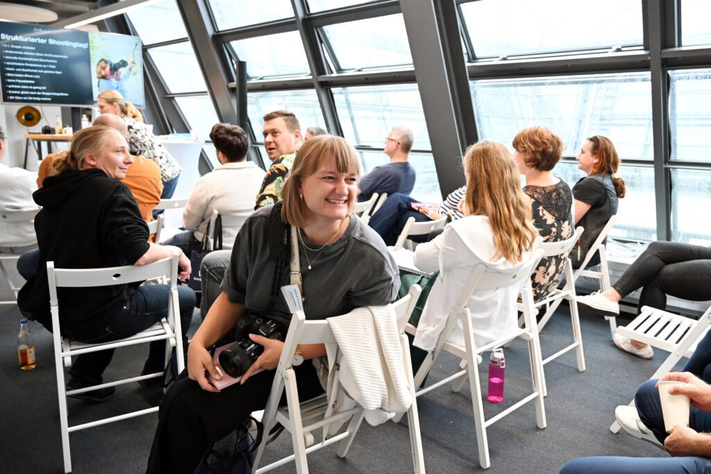 Drei Personen sitzen an einem runden Tisch und interagieren während eines Live Events.