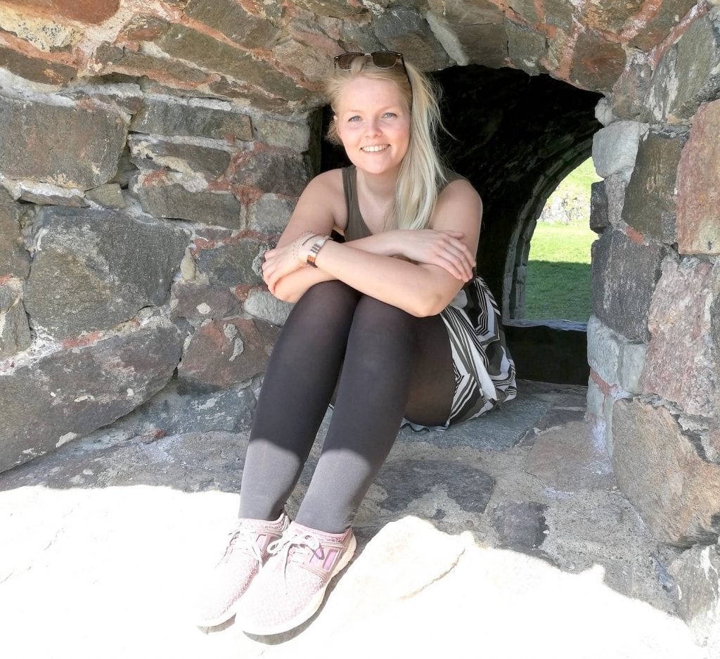 Sanna Niemi istuu kiviseinään upotetussa ikkuna-aukossa