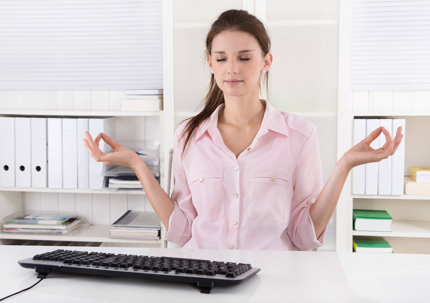 Frau meditiert am Arbeitsplatz.