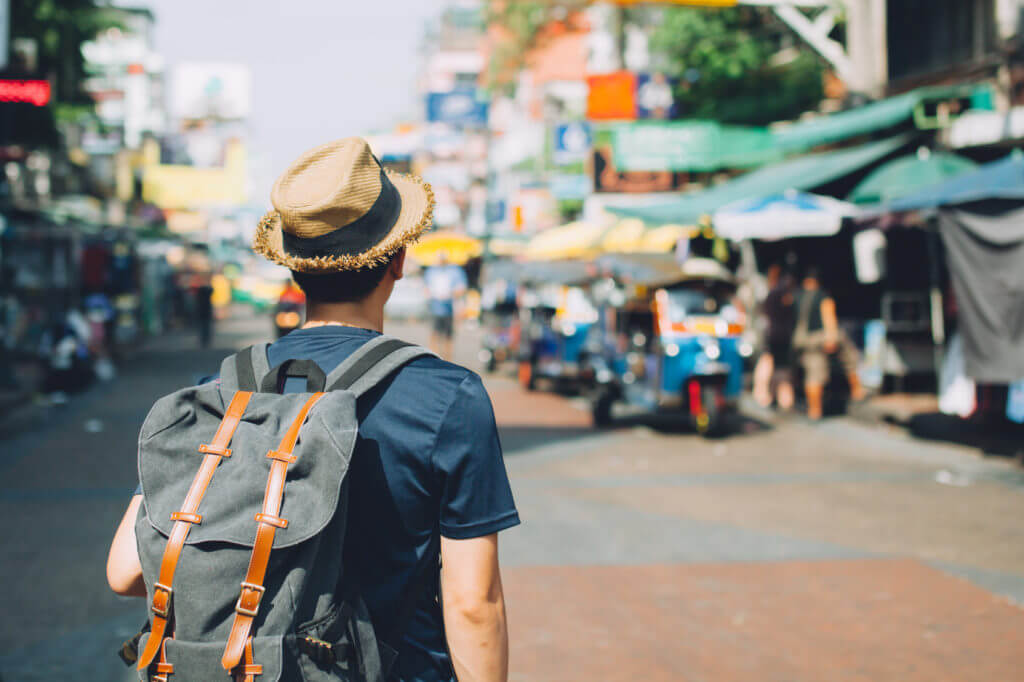 Backpack-Tourist mit Strohhut besucht Markt.