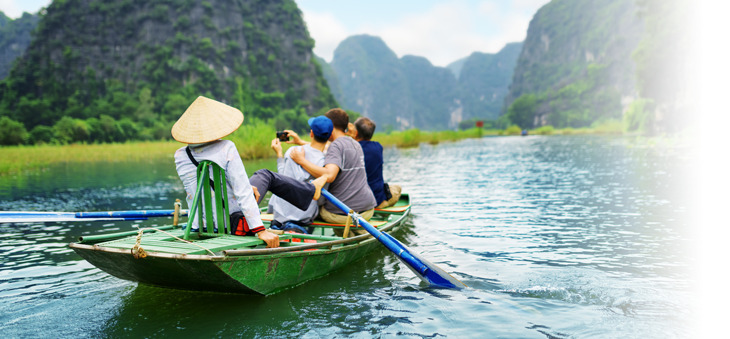 Kleines Boot mit Touristen und Bootsführer auf einem Fluss in Asien.