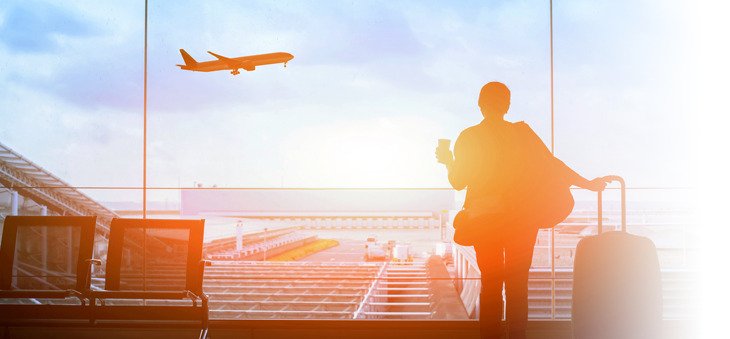Reisende am Flughafen sieht startendem Flugzeug zu.