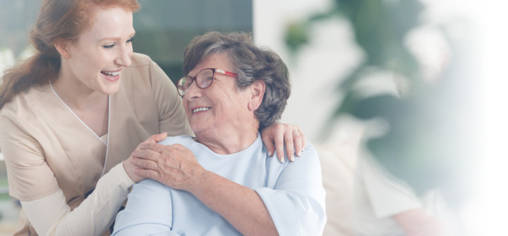 Seniorin berührt Hand einer jungen Frau.