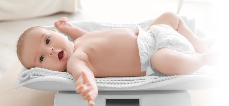 Baby mit Windel liegt auf einer Waage.