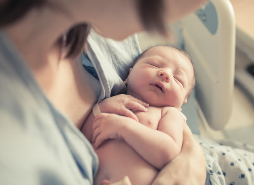 Baby schläft im Arm der Mutter.