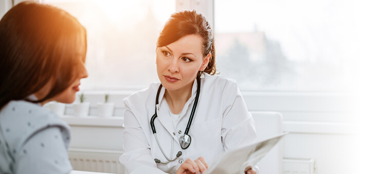 Ärztin und Patientin blicken auf ein Tablet-Display.