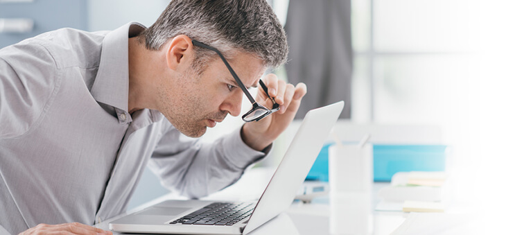 Mann versetzt Brille vor dem Laptop-Bildschirm.
