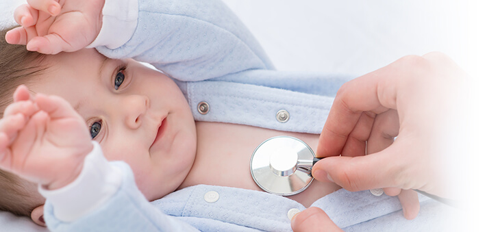 Baby hebt die Hände und wird an der Brust mit Stetoskop abgehört.