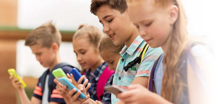 Kinder blicken auf Smartphones.