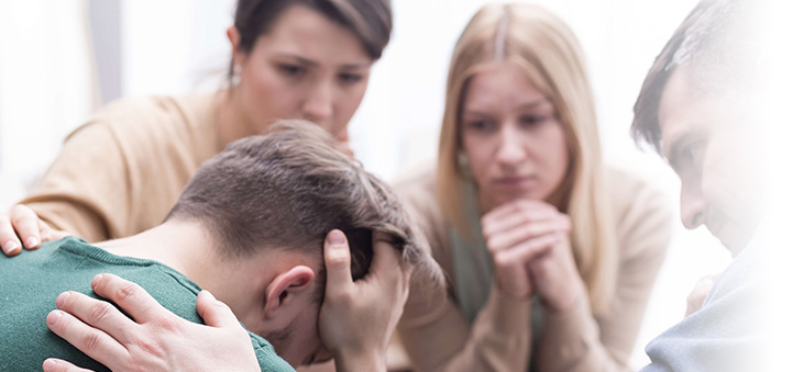 Depression bei Männern – Freunde troesten einen traurigen Mann.