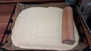 Pizzateig auf dem Backblech ausrollen Pizzateig auf dem Backblech ausrollen