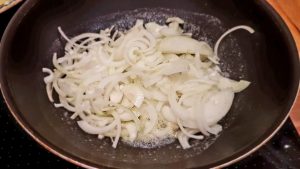 Zwiebeln in die Pfanne geben Zwiebeln in die Pfanne geben
