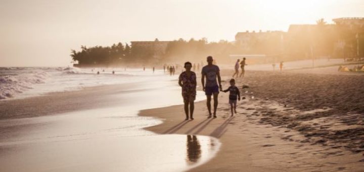 family of three walking on the beach at sunset