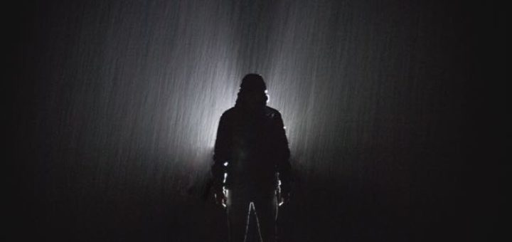 man standing in the rain at night