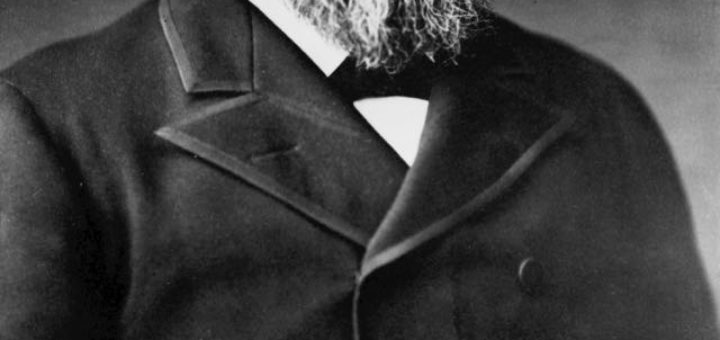 black and white photo of a man with beard in black trench coat
