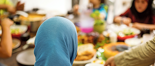 Muslim little girl having dinner at home with her family