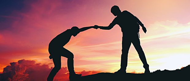 Teamwork couple helping hiking each other silhouette on mountain