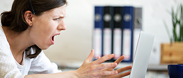 Young business woman screaming at laptop