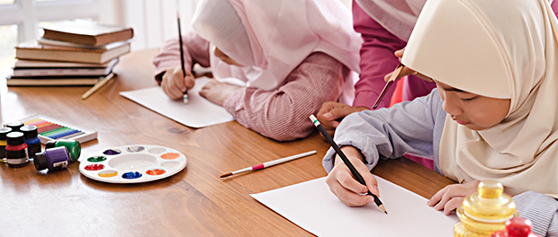 Muslim woman teaching her children painting and drawing at home.
