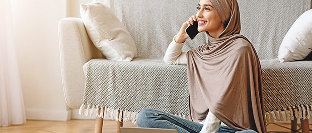 frau-kopftuch-wohnzimmer-lächeln-sprechen-telefon-laptop