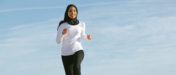 Front view of an arab saudi emirates woman running on the beach