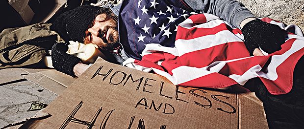 Homeless man sleeping outsie under American flag