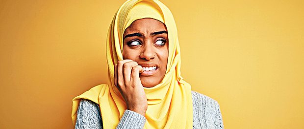 Young beautiful african american girl wearing muslim hijab over isolated yellow background looking stressed and nervous with hands on mouth biting nails. Anxiety problem.