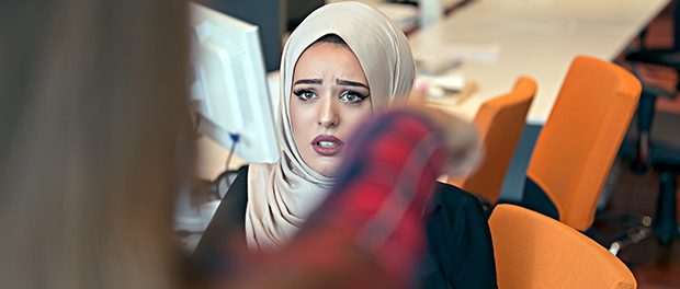 Worried arabic businesswoman wearing hijab receiving a notification from a colleague in her workplace at office