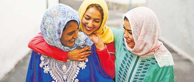Happy Muslim women walking in the city center - Arabian young gi