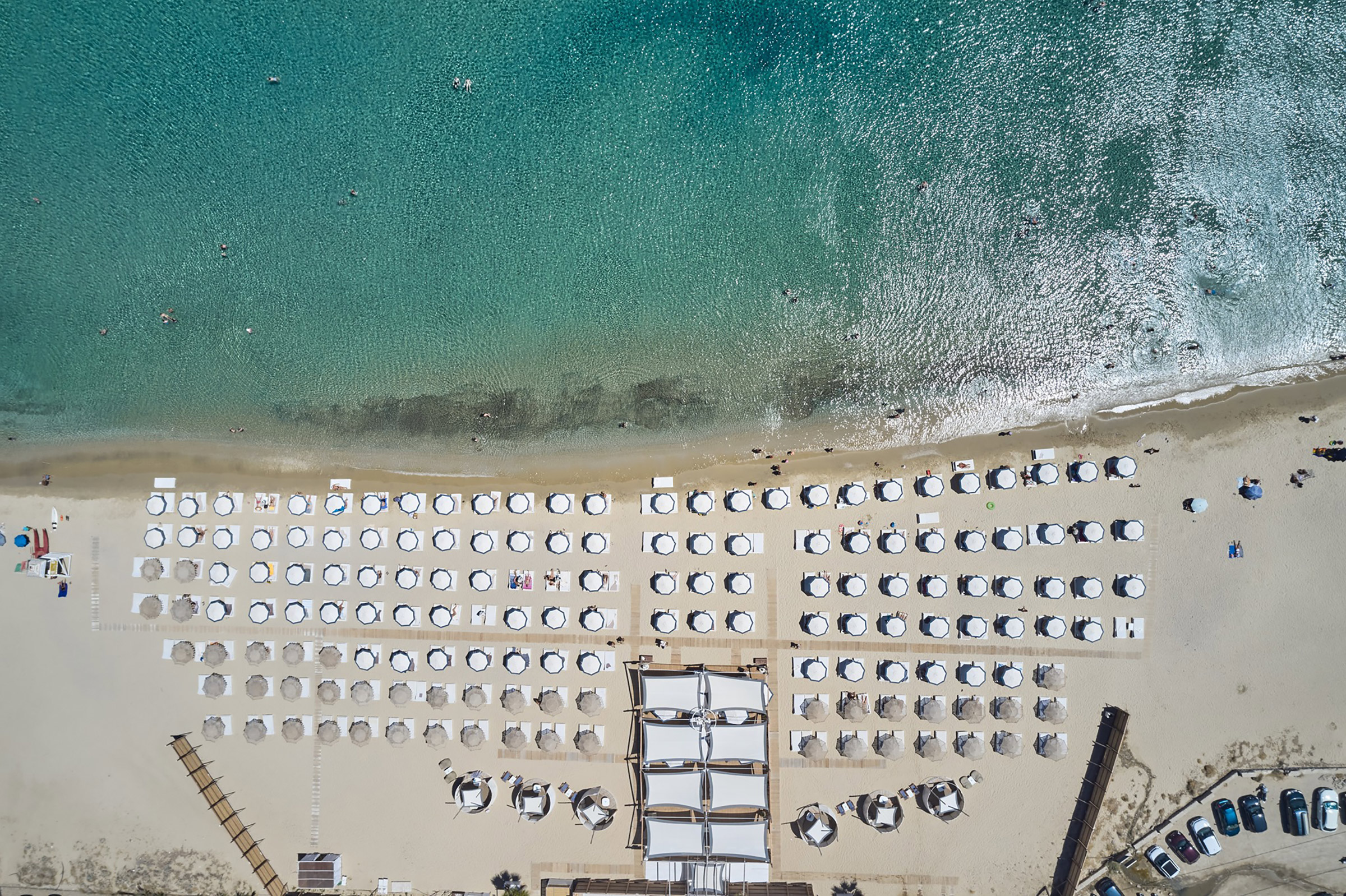 One of the most stunning beaches of Mykonos Island, the gold-sanded and shallow- watered endless bay of Kalo Livadi is home to the grand summer project of Lohan Beach House. - Secondary Image