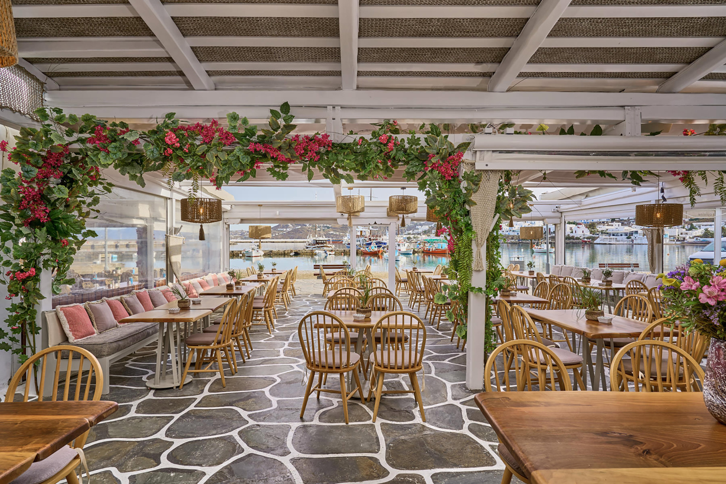 Making good use of natural elements, such as wood and wicker, and with earthly tones against a totally white background, Raya Mykonos provides its guests with a relaxing setting just on the shore of Mykonos Town. - Secondary Image