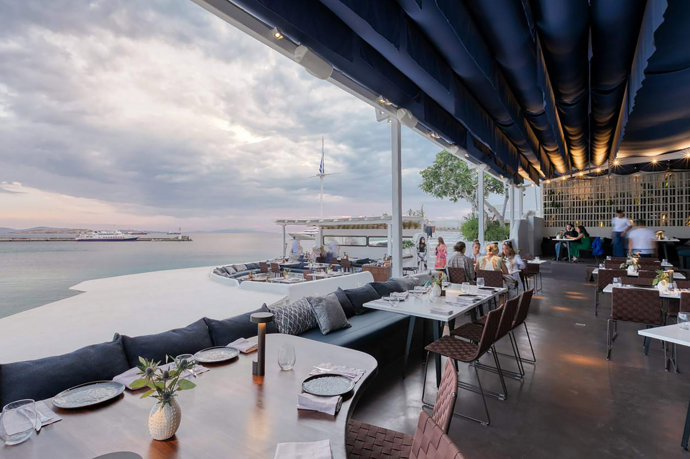 Gracefully nestled on the north end of Mykonos town, the legendary Remezzo offers one of the best views of the old port and an unappareled ambiance of summer bliss. Some of the best Mykonos stories begin with the phrase “and we were having a drink at Remezzo and…”, as this stunning venue has been part of the Mykonian nightlife myth since 1967. - Secondary Image