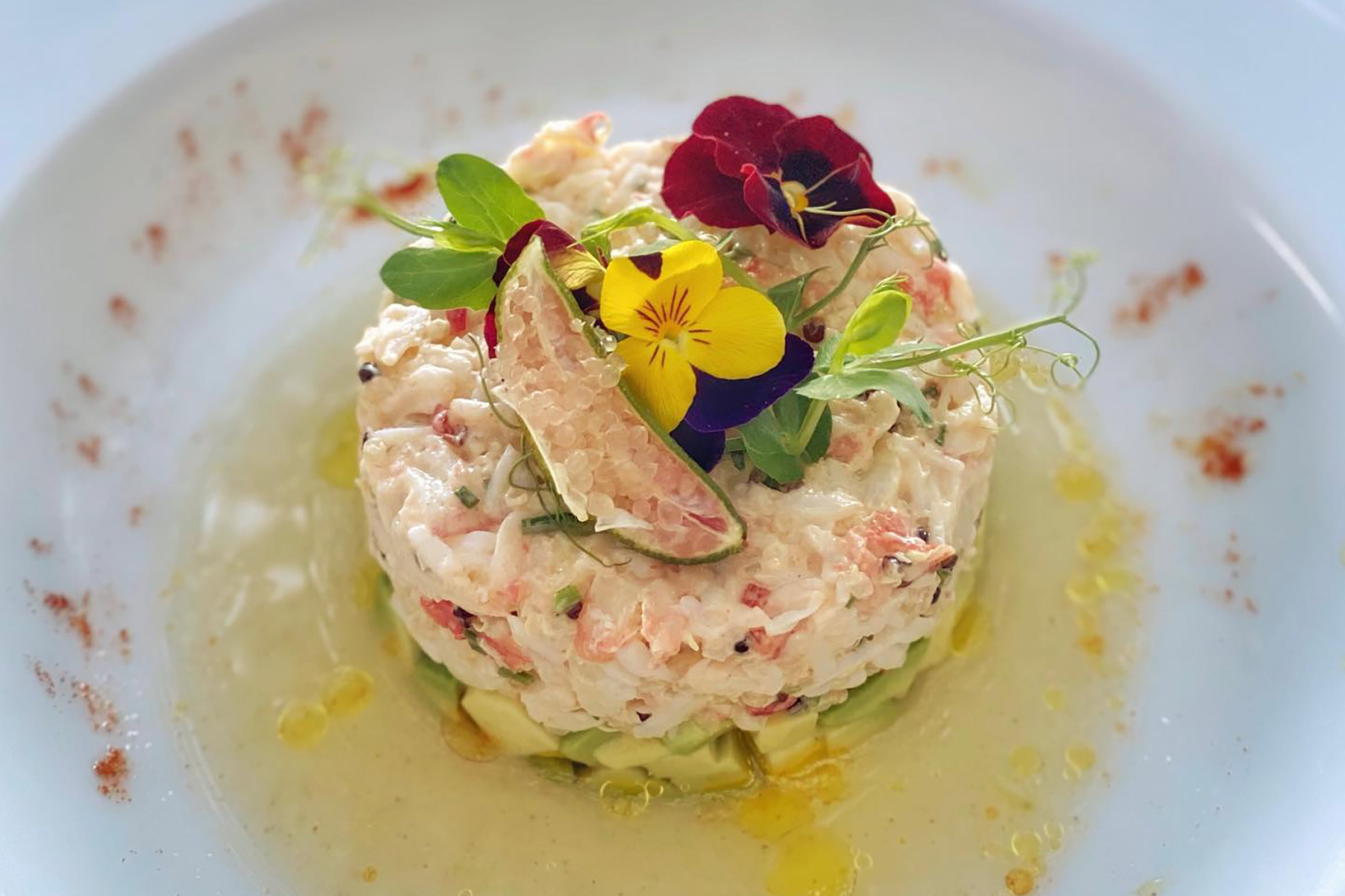 Literally hanging over the sea, here you will savour creative Mediterranean & Mykonian creations made with the freshest ingredients, coming directly from the sea, while your oysters, mussels, urchins, crayfish and lobsters wait for your order in a small natural sea pool, to be prepared before your eyes and transformed into mouth-watering delicacies and eye-catching dishes. - Secondary Image